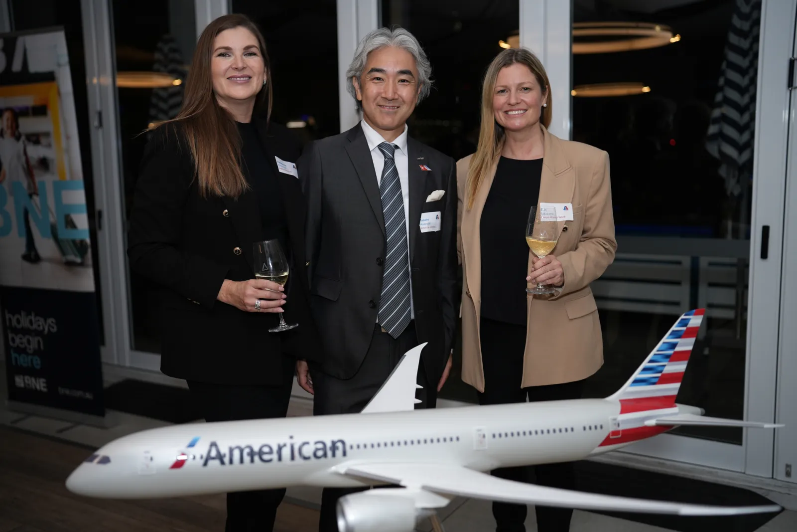 Delegates with drinks beside an American Airlines model aircraft at an AmCham trade event in Brisbane.